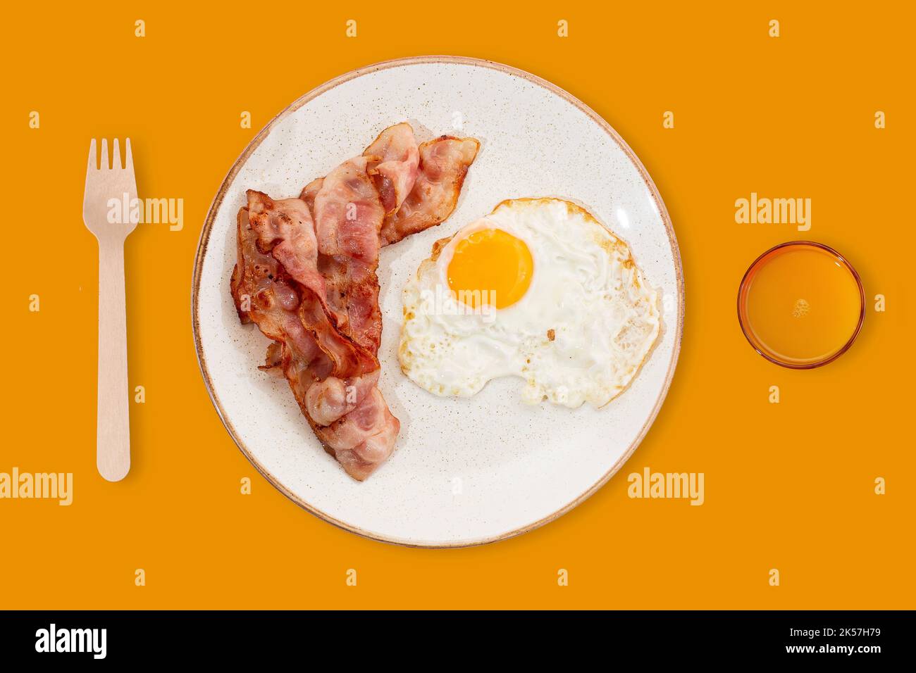 Das beste Frühstück. Speck, ein Spiegelei und Orangensaft. Foto auf einem Sommer gelben Hintergrund. Für Text platzieren. Marketing- und Werbeidee. Modern Stockfoto