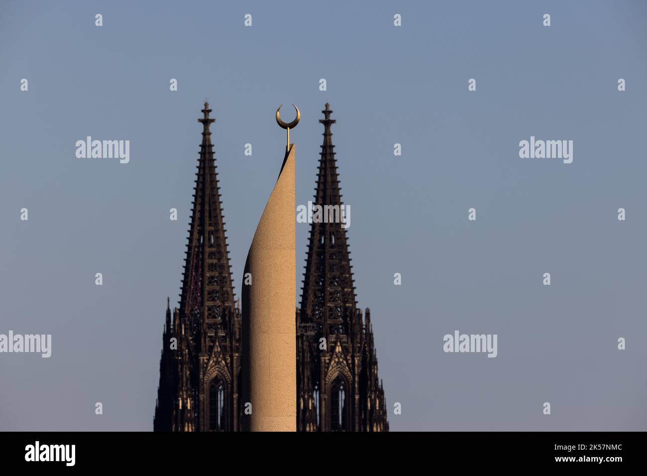 Köln, Deutschland. 06. Oktober 2022. Im Licht der untergehenden Sonne ist ein Minarett der zentralen Moschee der DITIB (Türkisch-Islamische Vereinigung des Instituts für Religion) und des Kölner Doms zu sehen. In der Kölner Zentralmoschee im Stadtteil Ehrenfeld konnte der Muezzin ab dem 14. Oktober 2022 über Lautsprecher zum Gebet aufrufen. Der Muezzin würde dann zwischen 12:00 und 15:00 Uhr Freitagsgebete für eine maximale Dauer von fünf Minuten fordern dürfen. Quelle: Rolf Vennenbernd/dpa/Alamy Live News Stockfoto