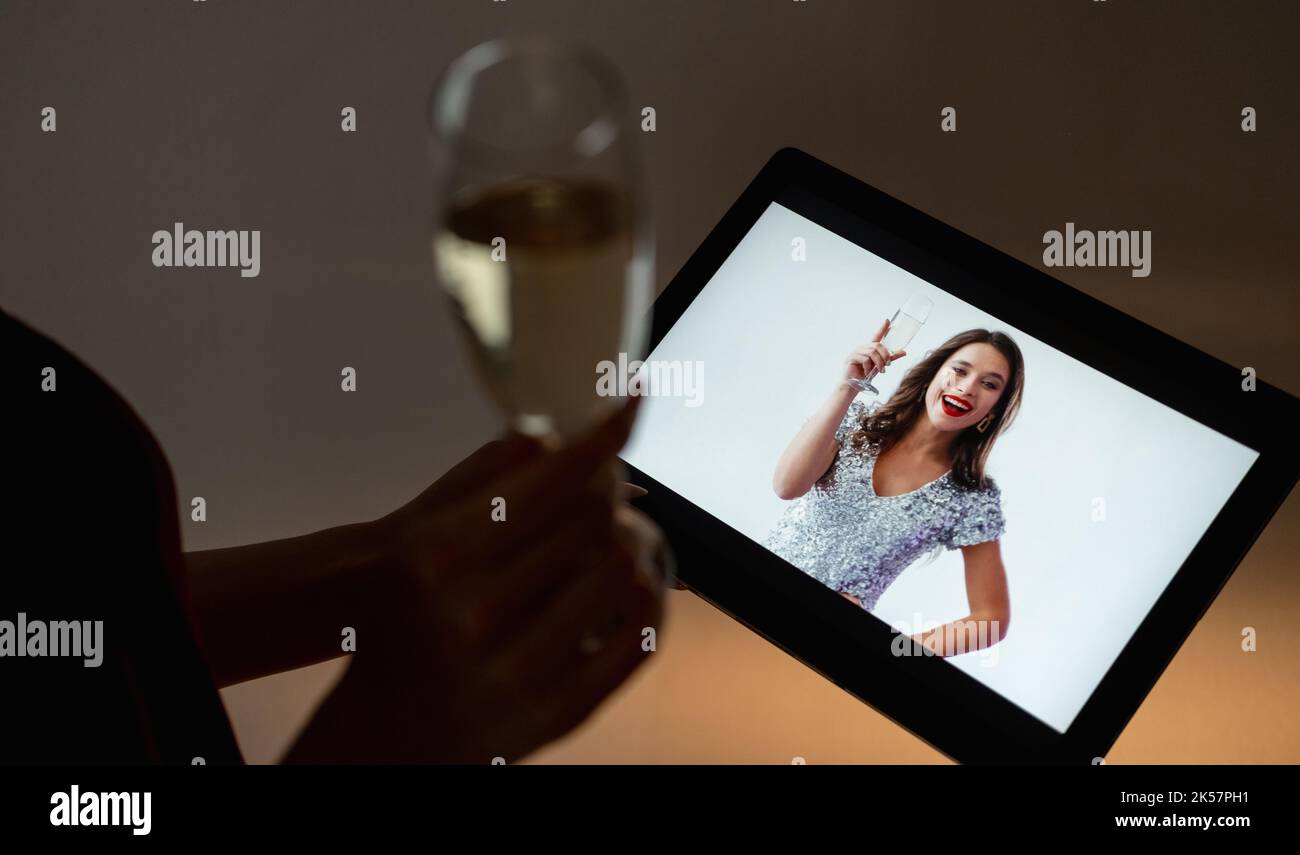 Online-Geburtstag. Festliche Begrüßung. Virtuelle Party. Unkenntlich Frau mit einem Glas Champagner aussehen glücklich weibliche Freundin gratuliert auf Tablet CO Stockfoto