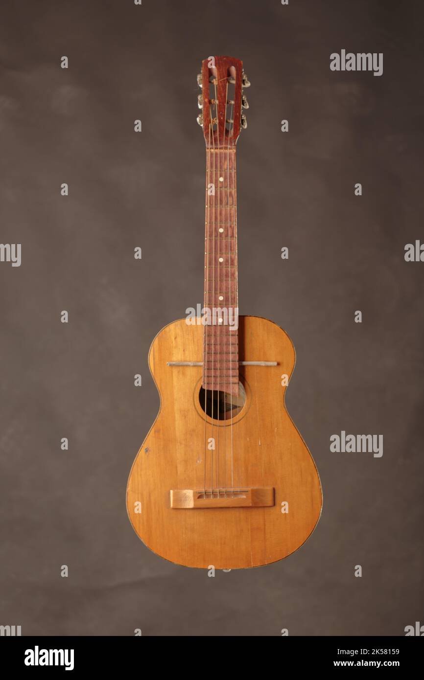Alte Gitarre gebrochene akustische Gitarre. Der Hintergrund ist braun. Nahaufnahme. Stockfoto