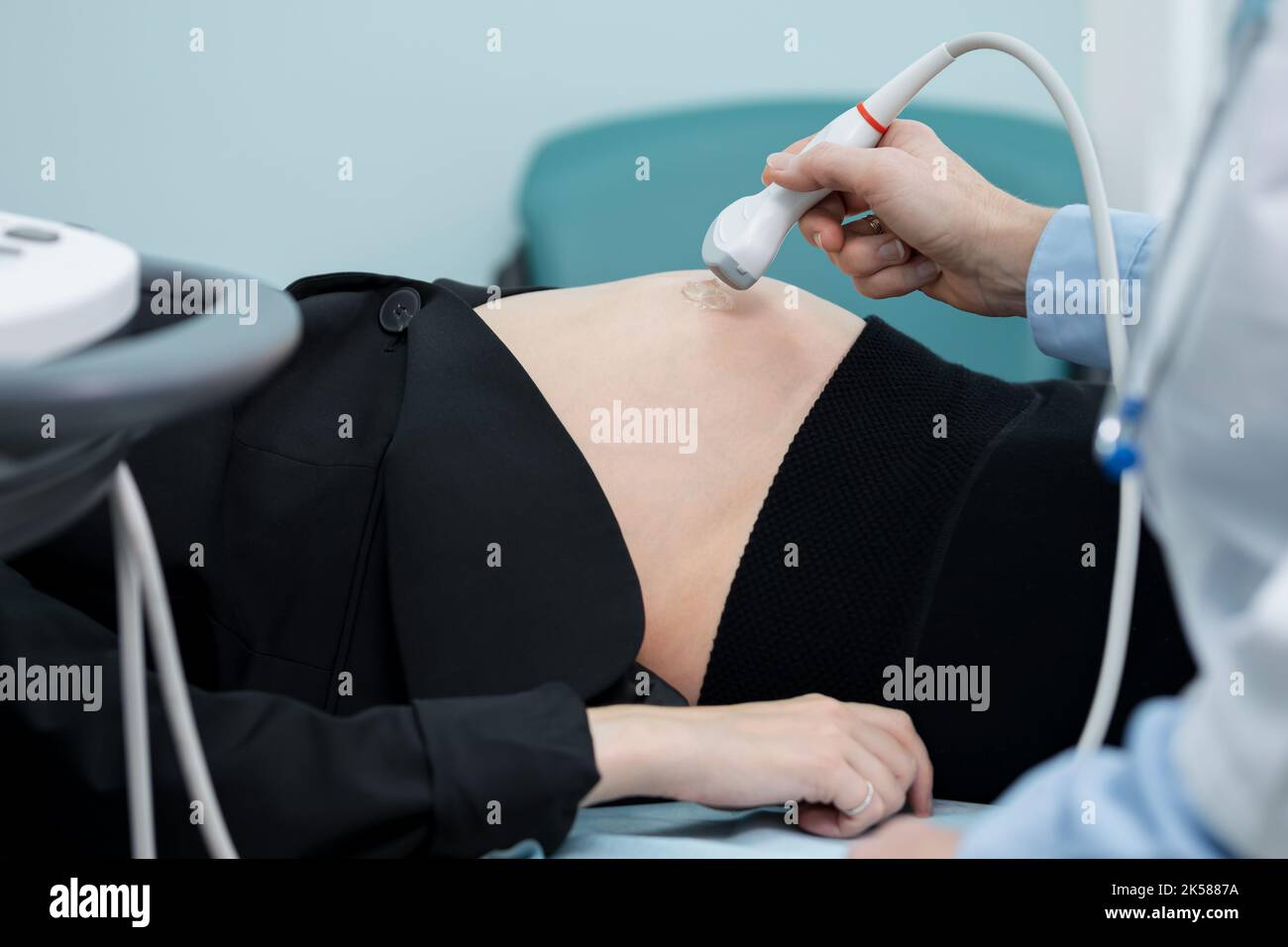 Die Hand schiebt den Schallkopf über den Abdomen und überprüft die Anzeichen eines Gestrüchs Stockfoto