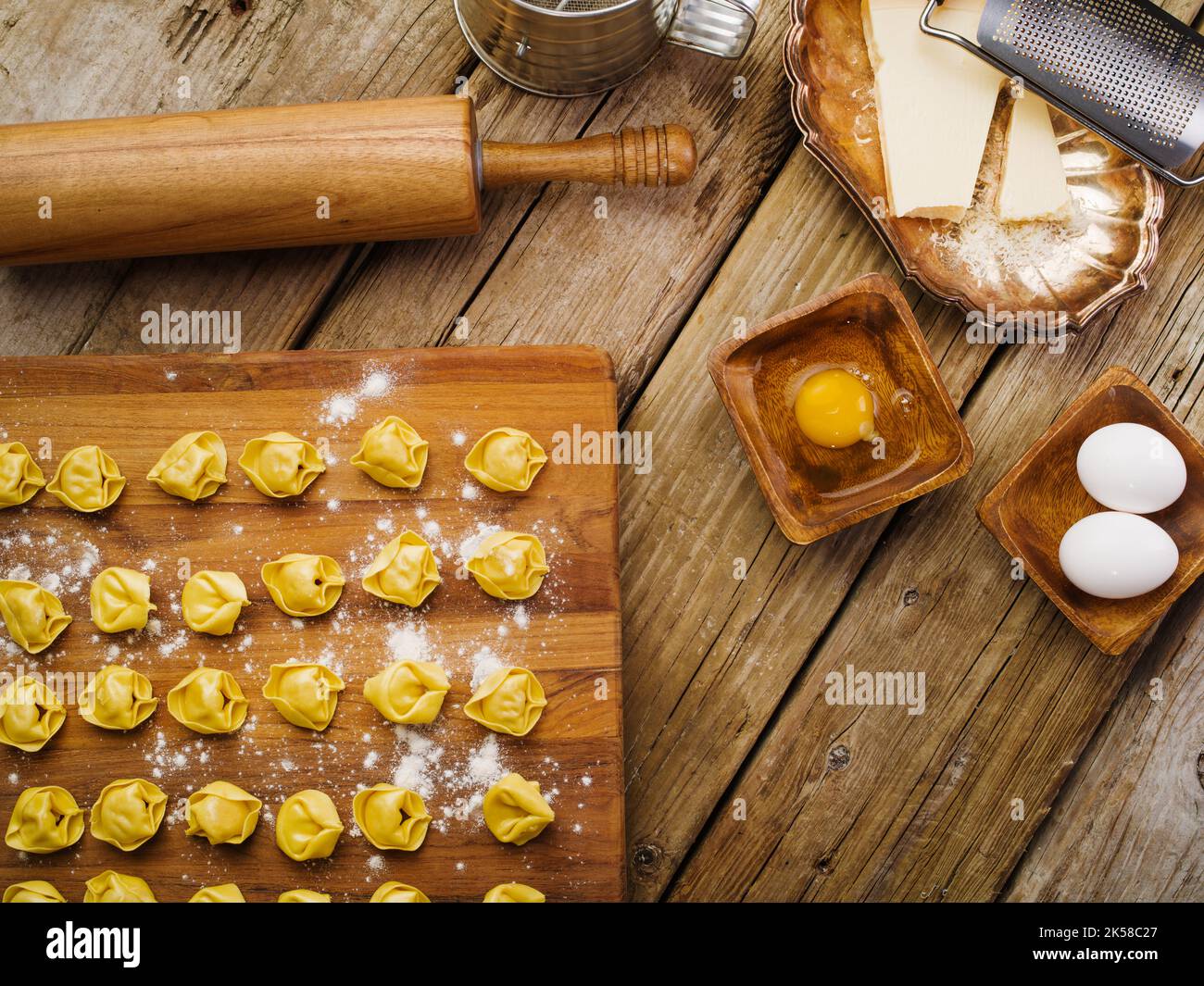Auf einem hölzernen Küchentisch, hausgemachte Knödel gefüllt mit Hackfleisch auf einem Schneidebrett, Küchenutensilien und Zutaten. Low-Angle-Ansicht. Rezepte f Stockfoto