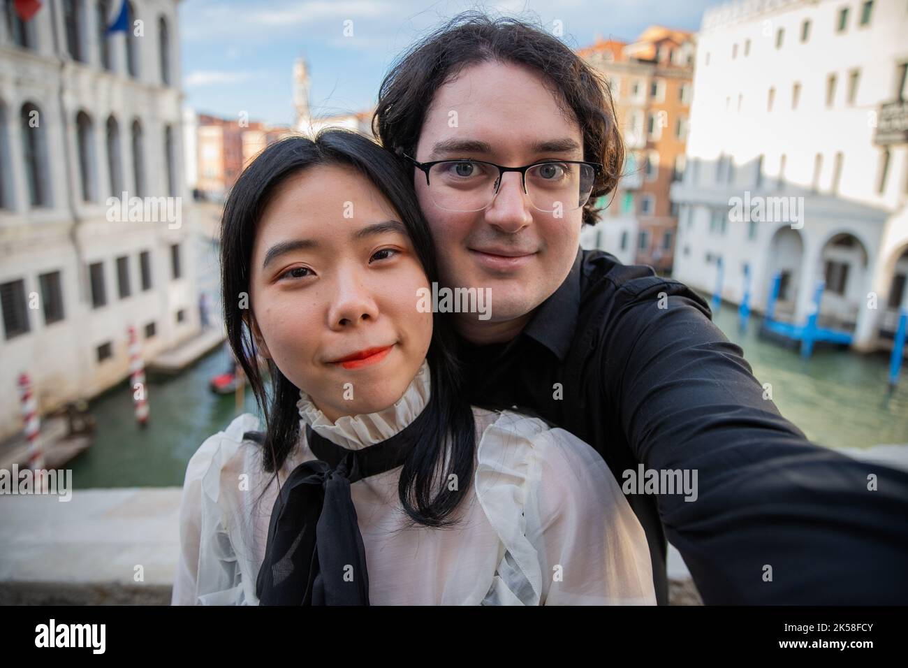Multirassisches Touristenpaar, das Venedig besucht, macht ein Selfie auf der Brücke und dem Kanal im Hintergrund. Stockfoto