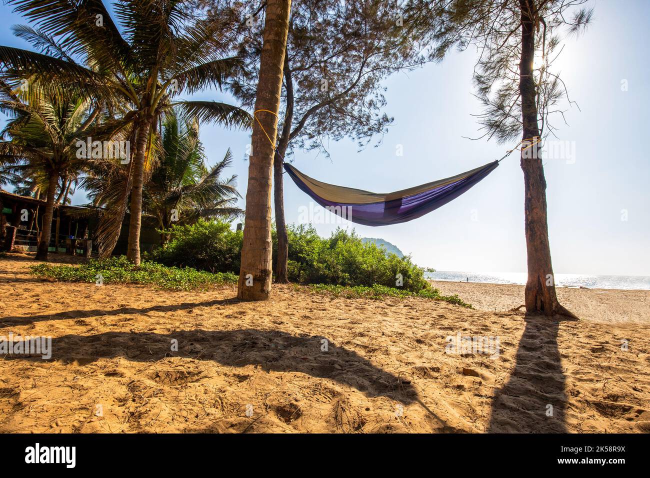 Hängematte und am Strand Nirvana im Bundesstaat Karnataka. Kleine Zahl von Menschen in der Ferne neben Wasser. Stockfoto