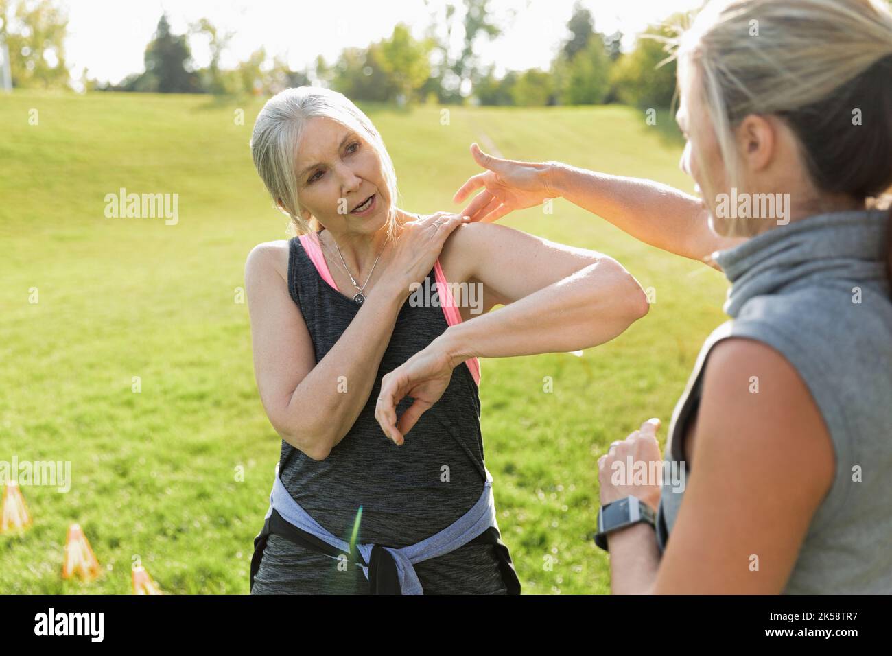 Ältere Frau erklärt dem persönlichen Trainer das Schultergelenk Stockfoto