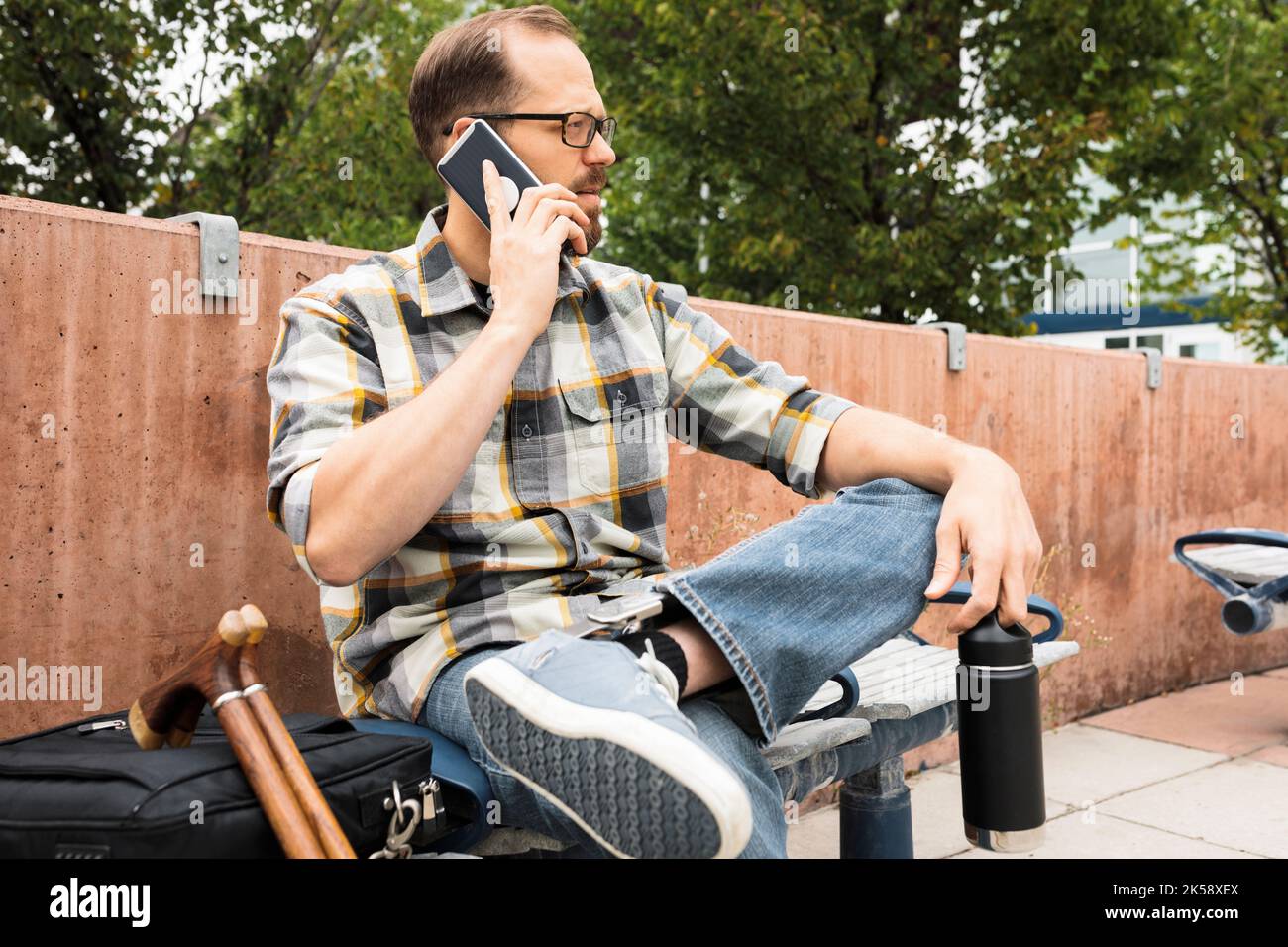 Mittelerwachsener Mann mit Smartphone auf der Bank Stockfoto