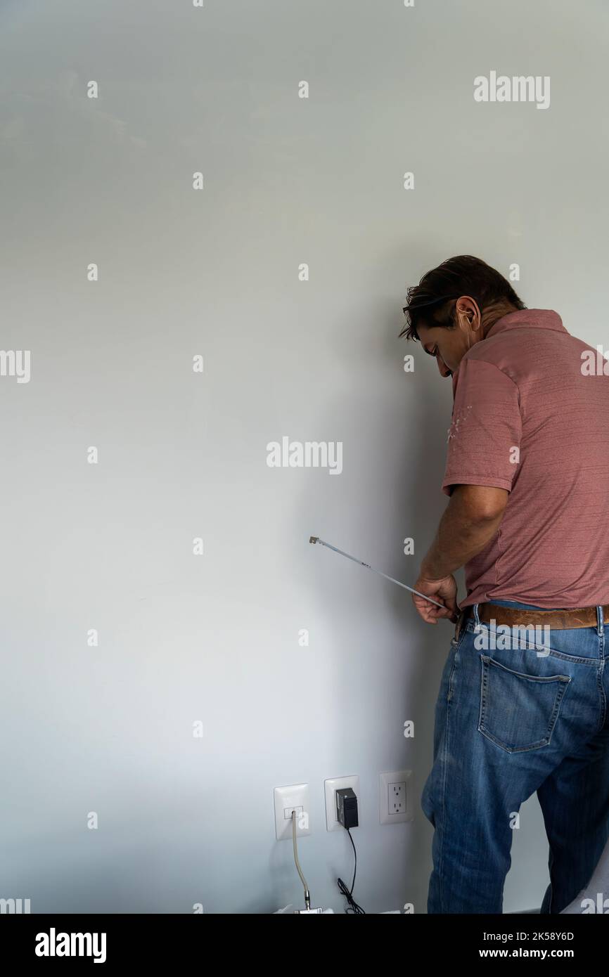 Senior Mann messen Wand mit Maßband Reparatur Wohnung. Reifer Ehemann renovieren Haus Stockfoto