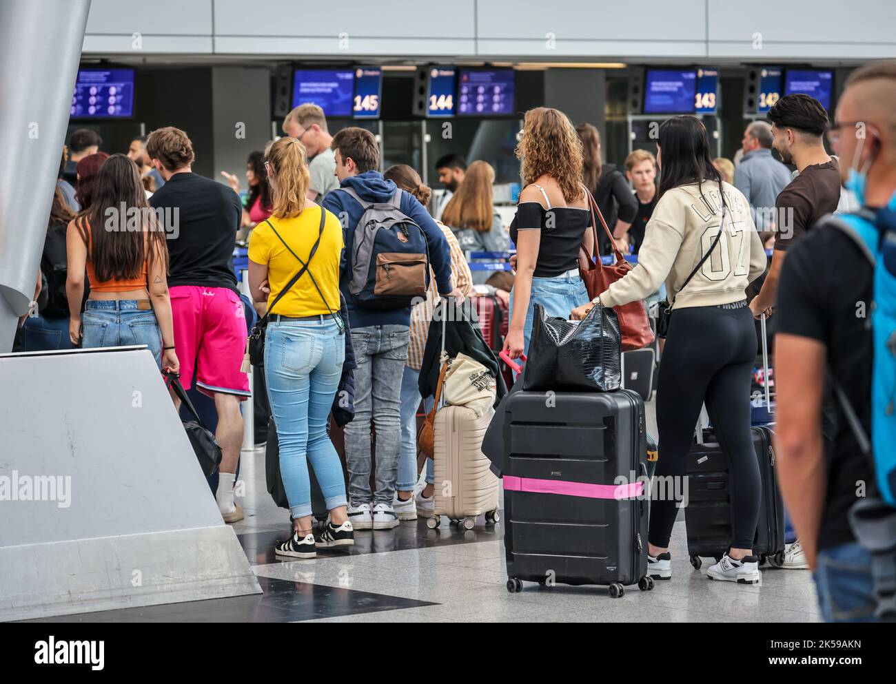 27.07.2022, Deutschland, Nordrhein-Westfalen, Düsseldorf - Düsseldorf Airport, Urlauber stehen mit Koffern am Check-in-Schalter am Tag der Stockfoto