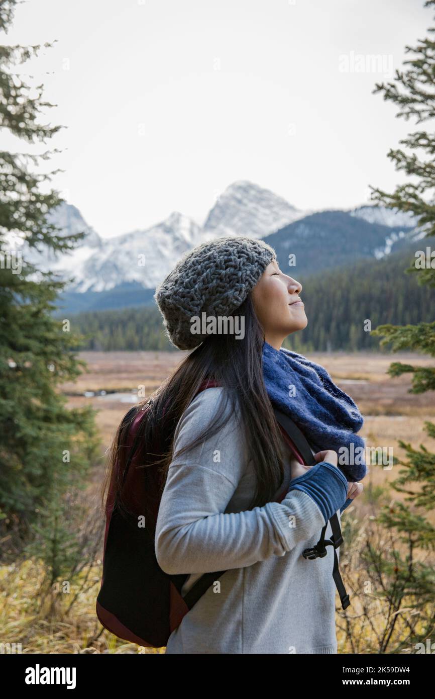 Ruhige Frau, die in ruhigen Wäldern mit Blick auf die Berge, in den Rocky Mountains, Kanada, wandert Stockfoto