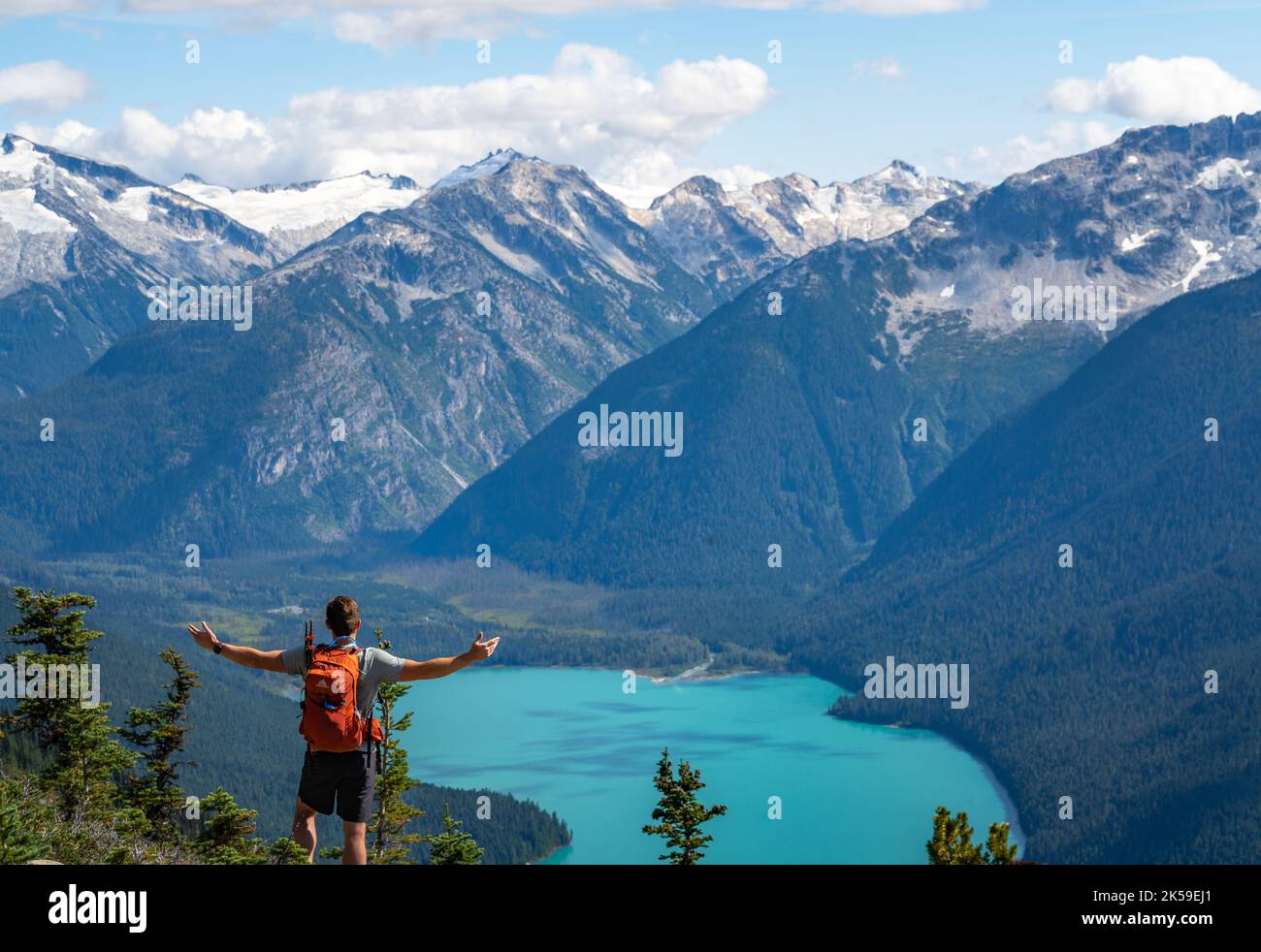 Der Mann steht in Ehrfurcht vor einem wunderschönen Blick auf die Berge und den alpinen See in der Nähe von Whistler, British Columbia in Kanada. Stockfoto