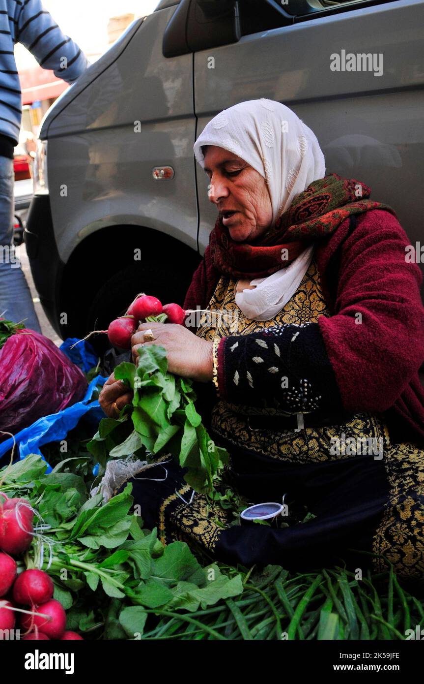 Eine palästinensische Frau, die Gemüse und Rettich auf einem Markt in Ostjerusalem verkauft. Stockfoto