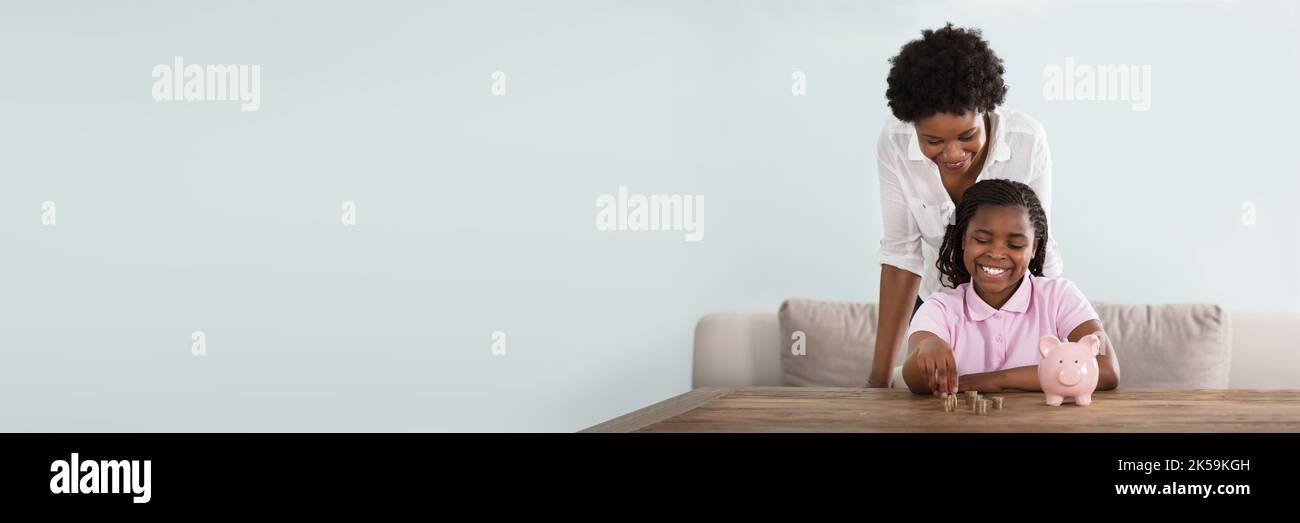 Afroamerikanisches Kind Spart Geld In Piggy Bank Stockfoto