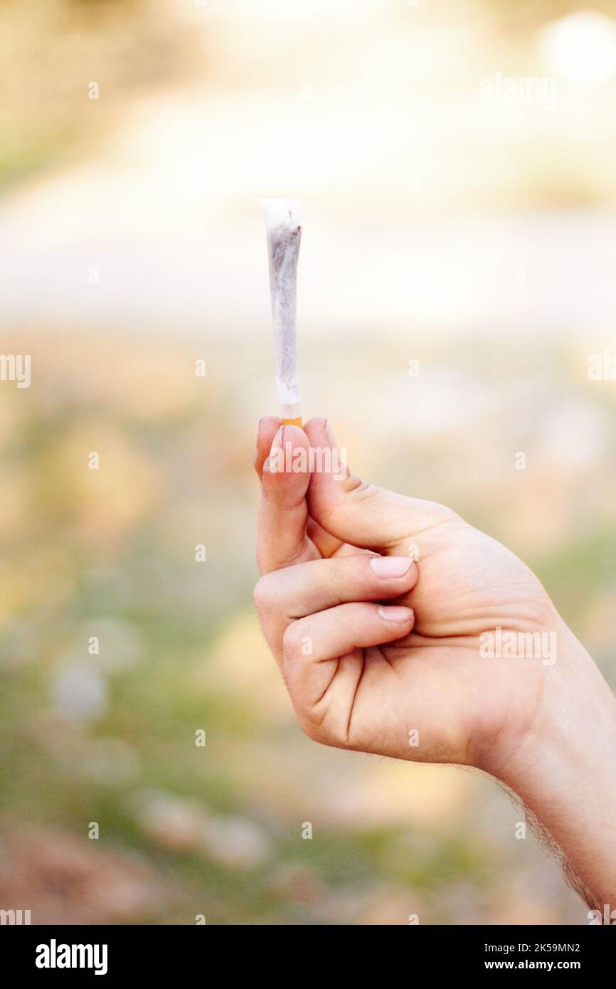 Alles hat ein Tor. Eine unkenntliche Person, die ein großes Marihuana-Gelenk hält. Stockfoto