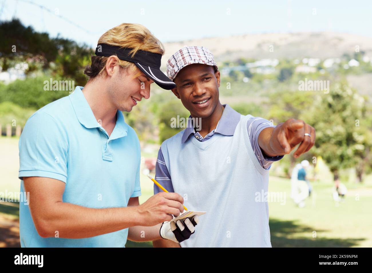 Zwei Freunde markieren ihre Golf-Scorecard und lachen. Stockfoto