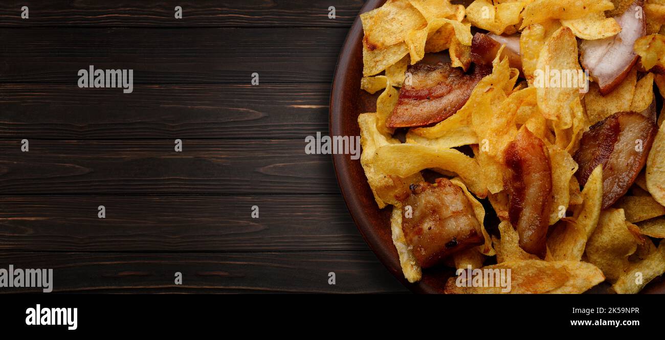 Kartoffelchips mit Speck auf einem Teller auf einem hölzernen Hintergrund Stockfoto