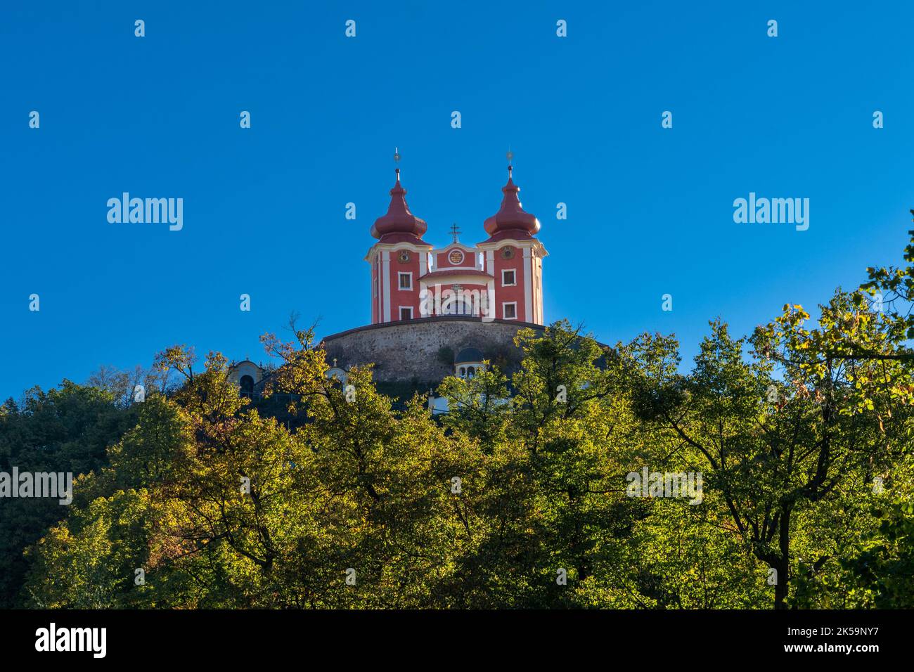 Banska Stiavnica, Slowakei - 28. September 2022: Blick auf den roten Kalvarienberg Banska Stiavnica unter einem blauen Himmel mit Wald im Vordergrund Stockfoto