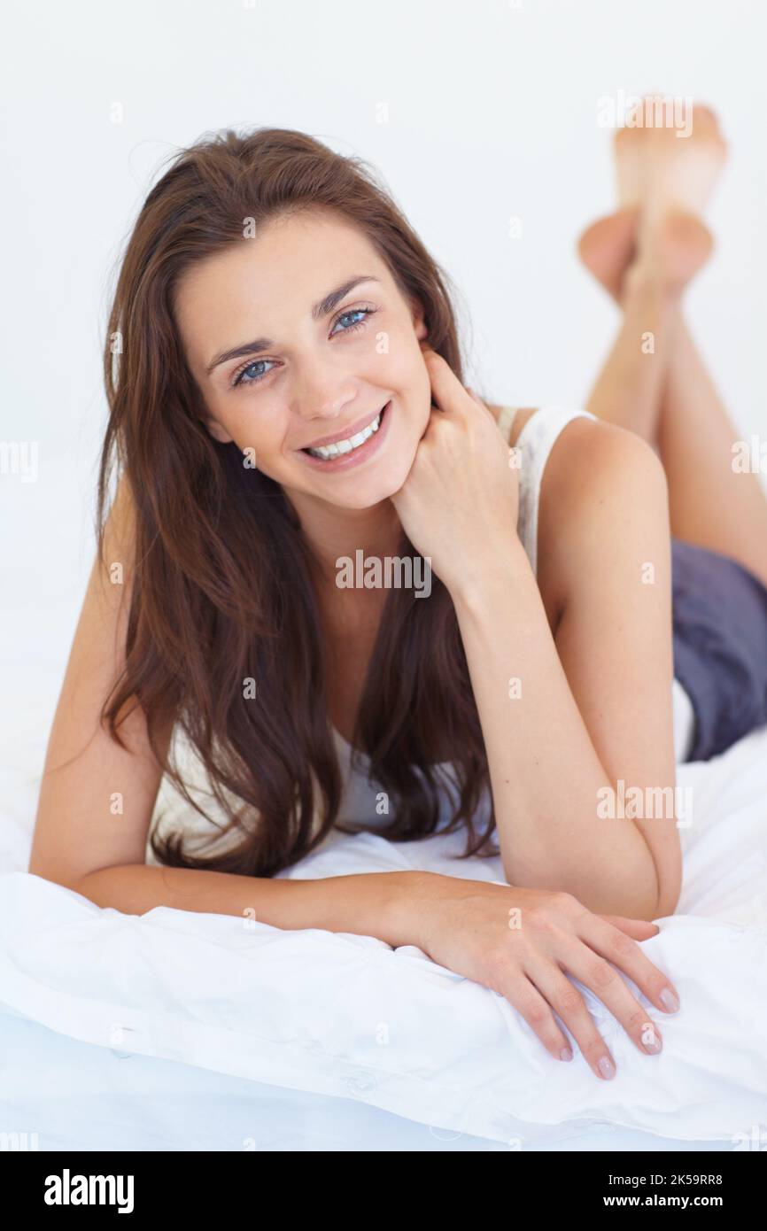 Entspannte Schönheit. Porträt eines hübschen Teenagers, das die Kamera anlächelt und sich auf ihrem Bett entspannt. Stockfoto