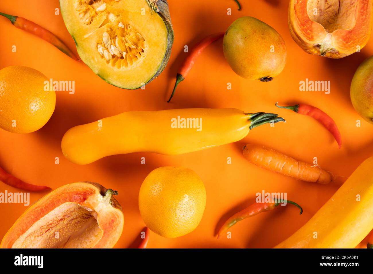 ORANGE MONOCHROM: Ein Flachbild, das orangefarbenes, nahrhaftes frisches Gemüse und Obst mit dem gleichen farbigen Hintergrund zeigt Stockfoto