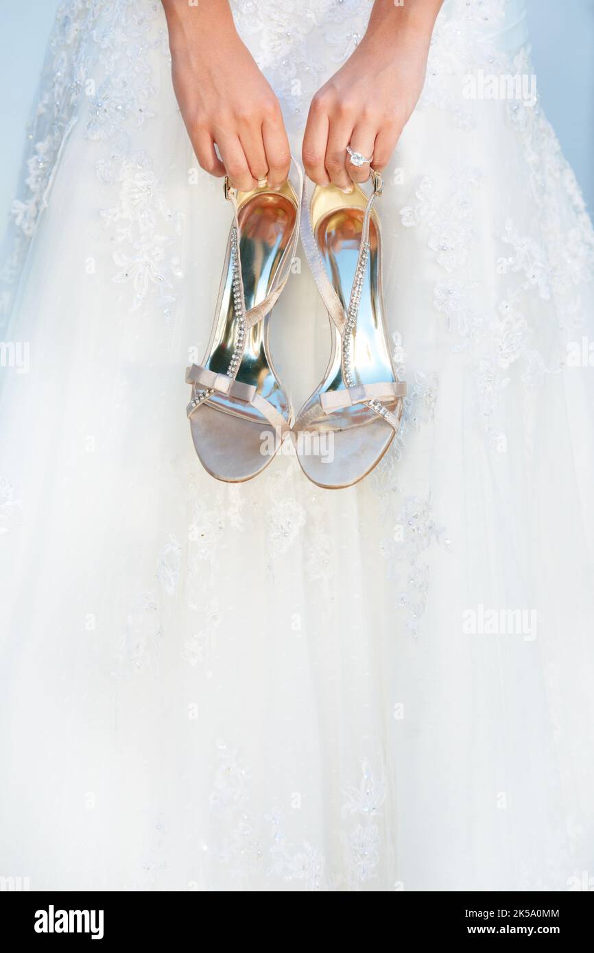 Hochzeitsaccutrements. Eine Braut hält ihre High Heels vor sich. Stockfoto