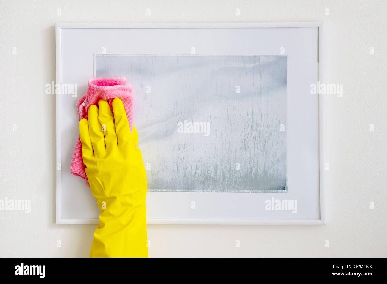 Hausmeisterservice. Hausreinigung. Chores Company. Nicht erkennbare weibliche Hand in gelben Schutzhandschuhen, die Bild-Kunst von Staub-Mikrofaserklumpen befreien Stockfoto