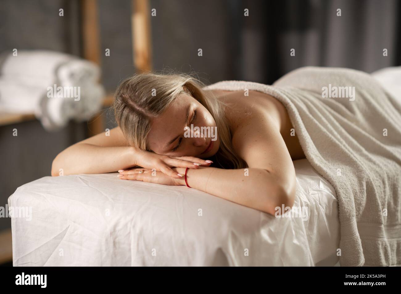 Entspannte Frau, die mit geschlossenen Augen im Spa liegt und auf eine Massage wartet. Mädchen mit Entspannung in Spa-Massage-Salon. Stockfoto