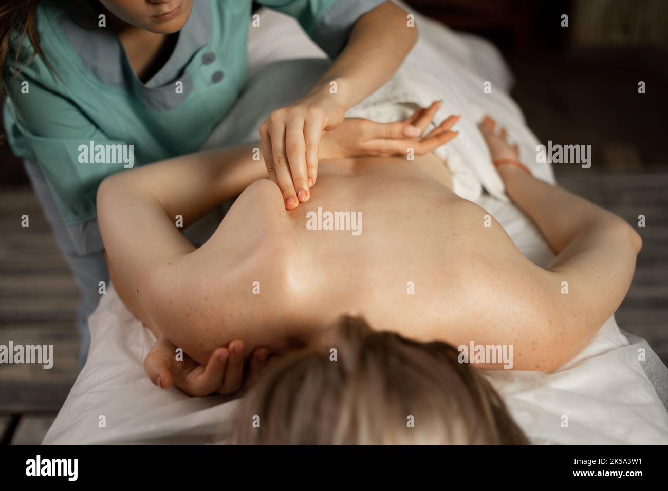 Masseur oder Chiropraktiker, der das Schulterblatt an die Frau im medizinischen Zentrum anpasst. Weibliche Patientin erhält eine Heilkörpermassage im Physiotherapiezentrum. Stockfoto
