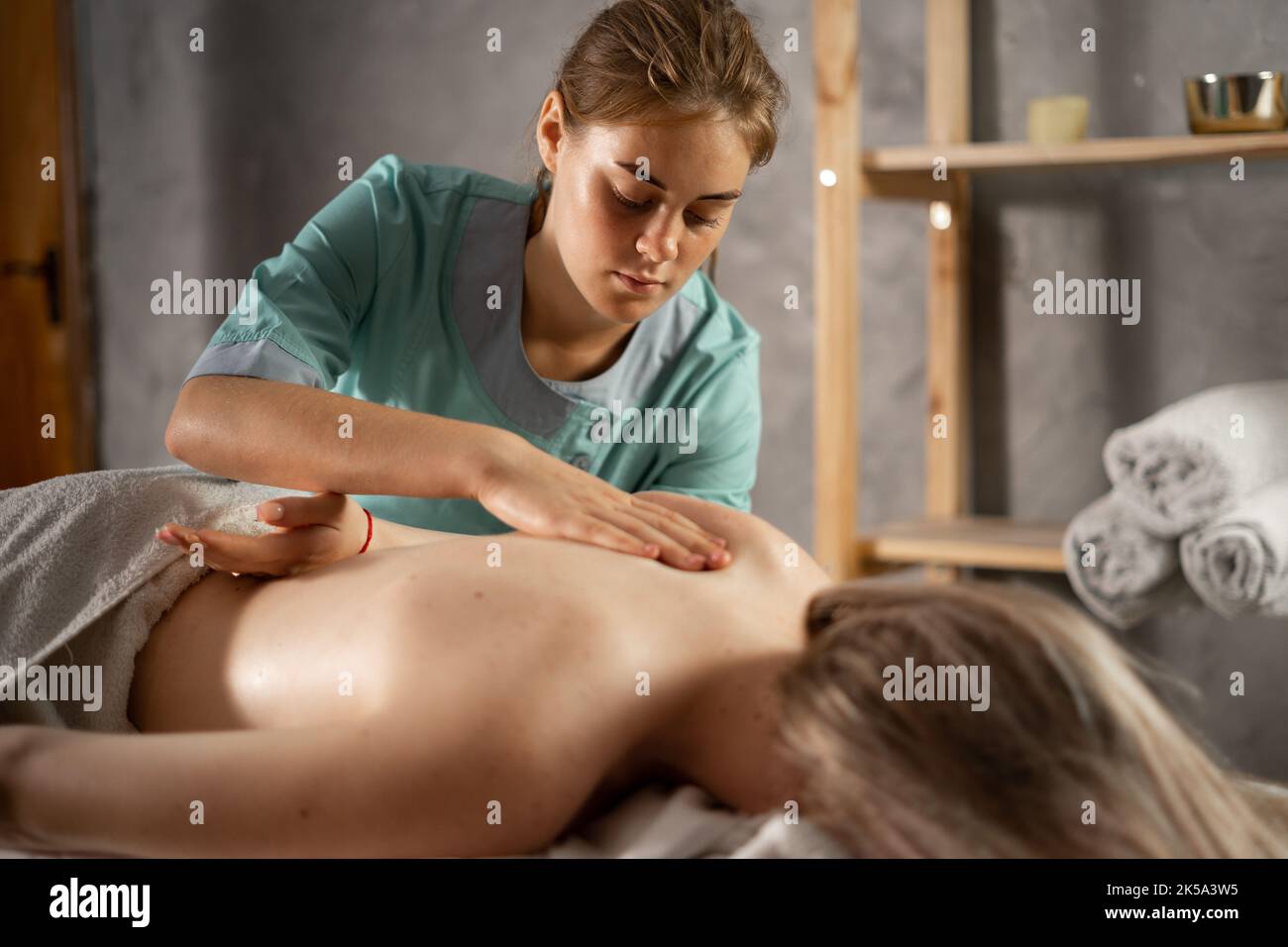 Masseur massiert Schulter der jungen Frau. Weibliche Patientin erhält heilende Körper- und Schulterblatt-Massage, die Schmerzen lindert und die Muskeln entspannt. Stockfoto