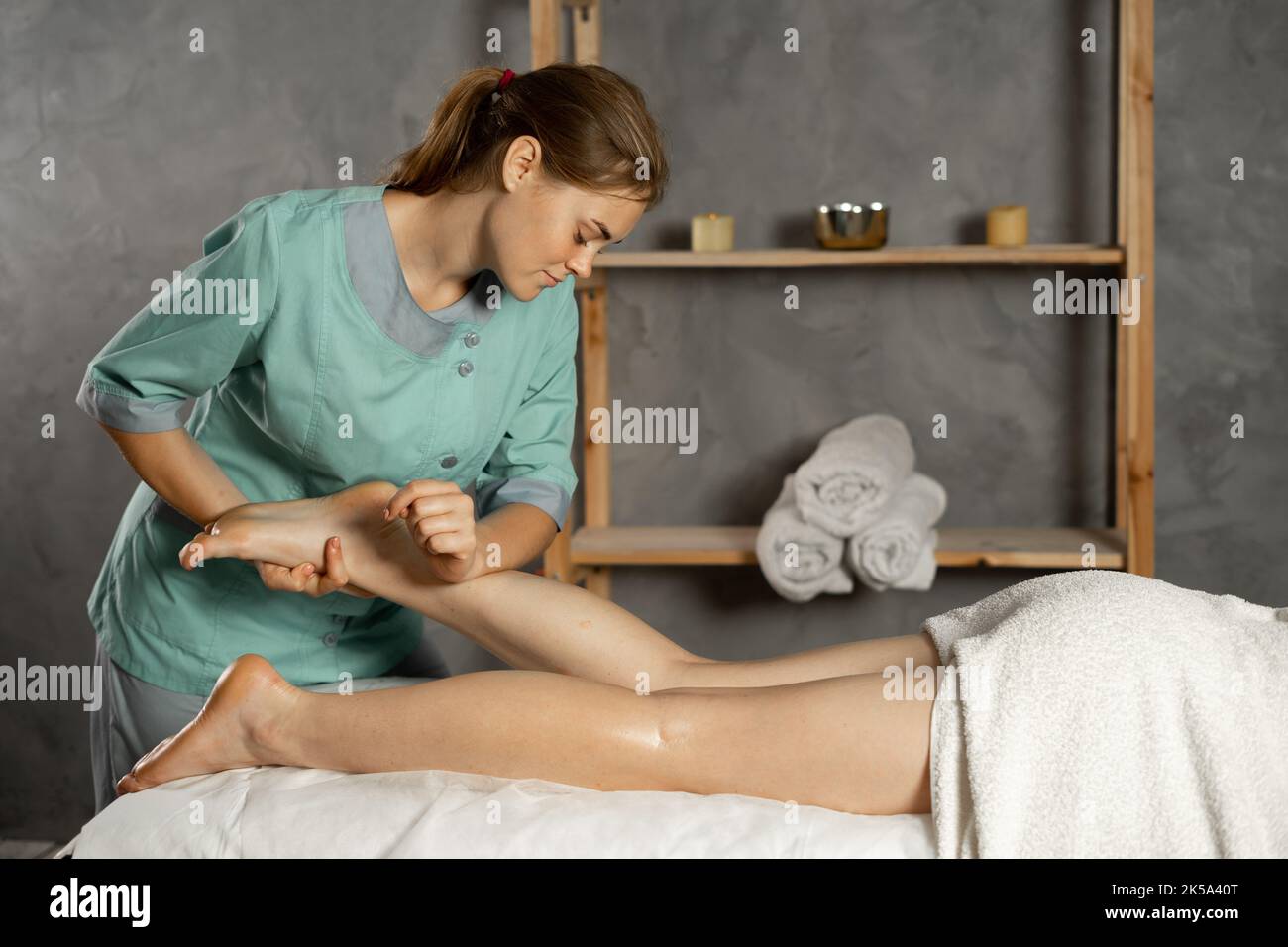 Lymphdrainage-Massage der Wadenmuskulatur.Therapeut, der Druck auf das weibliche Bein ausübt. Masseur massiert Beine der jungen Frau im Spa. Stockfoto