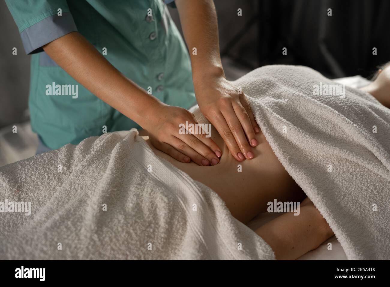 Nahaufnahme der Hände, die den weiblichen Bauch massieren. Therapeut übt Druck auf den Bauch aus. Körperformende Massage, Lymphdrainage, manuelle Eingriffe. Frau Stockfoto