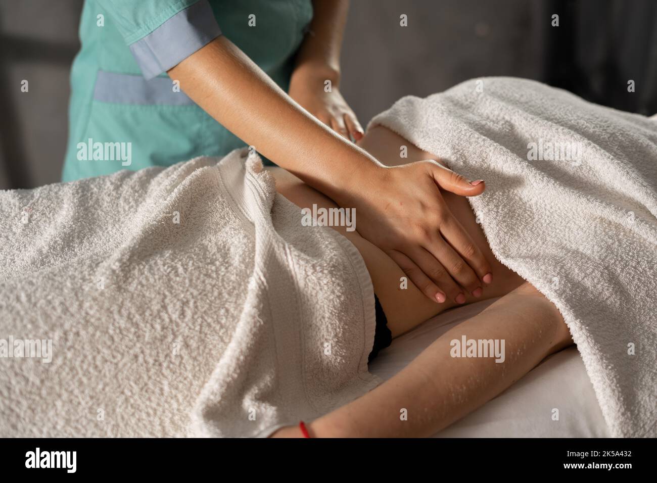Hände massieren weiblichen Bauch. Makro-Nahaufnahme des Therapeuten, der Druck auf den Bauch ausübt. Thai entspannende Magenmassage Stockfoto
