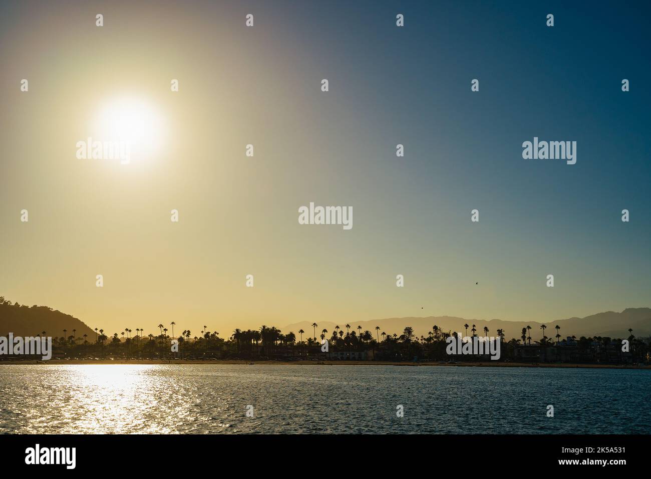 Perfekter goldblauer Santa Barbara Strand mit Palmen Silhouetten gegen Hügel und Meer. Urlaub Glückseligkeit in tropischen Lagen Natur Reise Landschaft Stockfoto