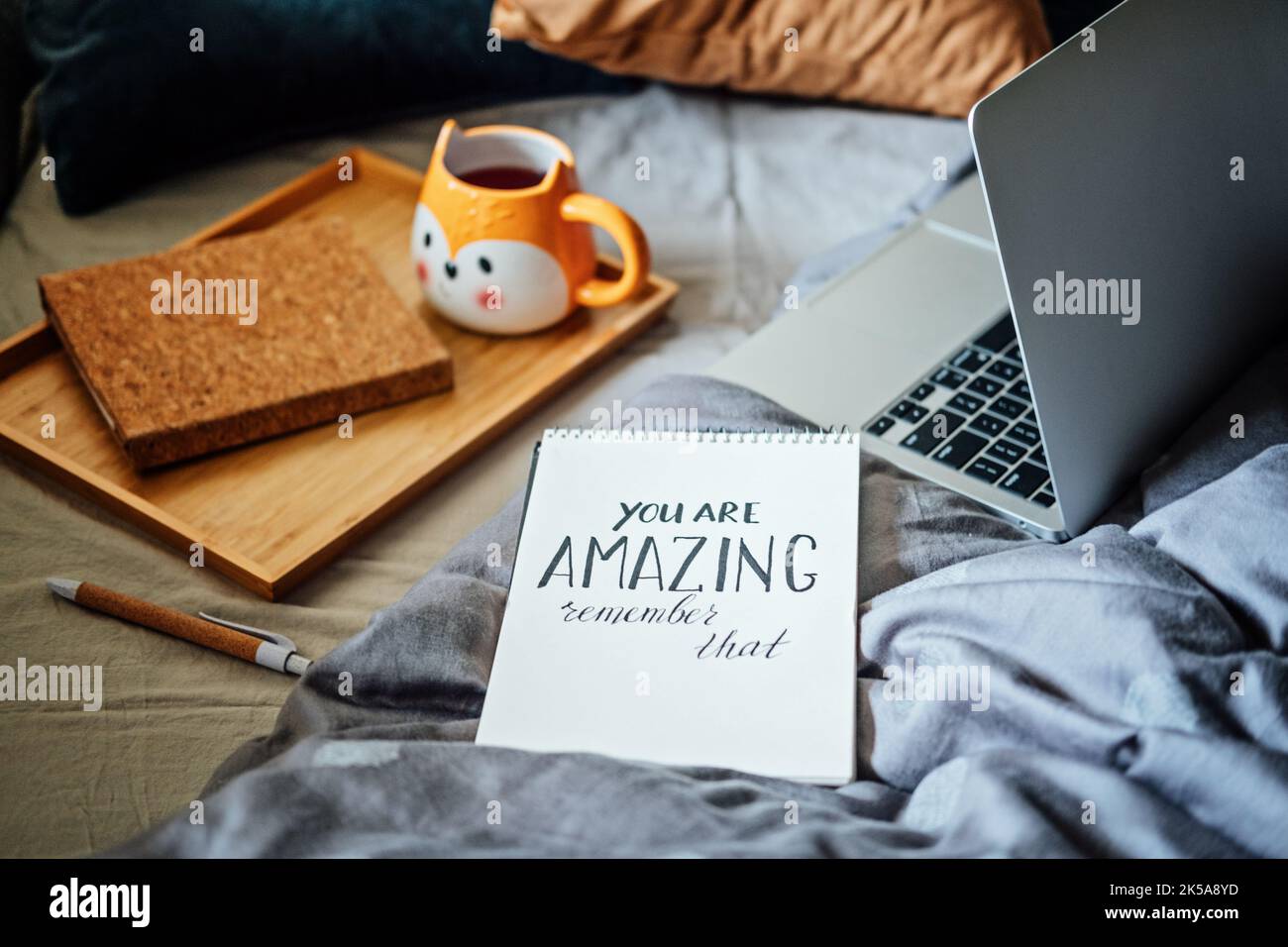 Positive tägliche Affirmationen für die Selbstliebe. Worte, die Sie sind erstaunlich in Notebook in der Nähe Laptop und Tee-Kaffee-Tasse in Bad zu Hause. Handschriftliche Bestätigungen Stockfoto
