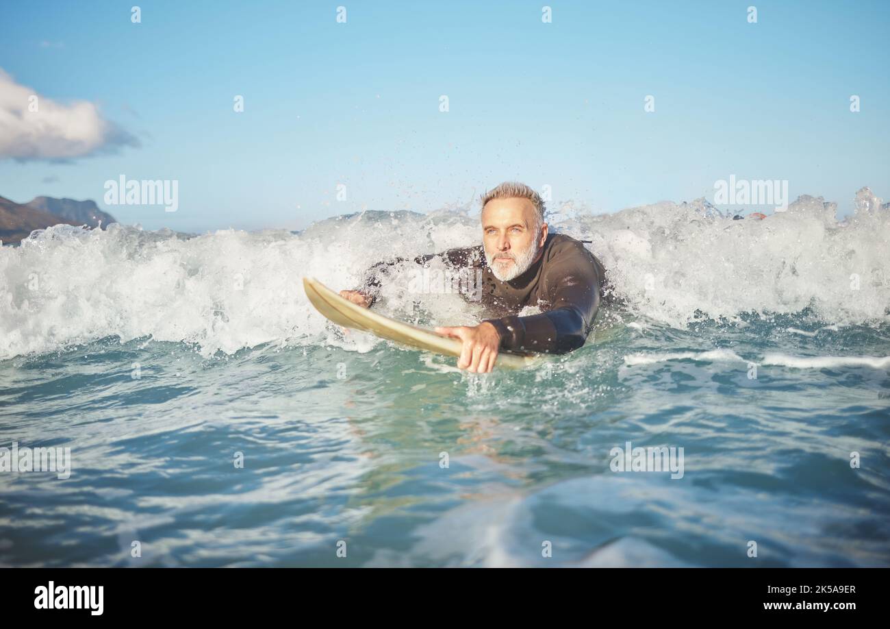 Ocean Waves, Senior man beim Surfen am Strand und gesunder Fitness-Lifestyle in Australien Sommerurlaub. Ältere Surfer schwimmen mit Surfbrett, Meerwasser Stockfoto