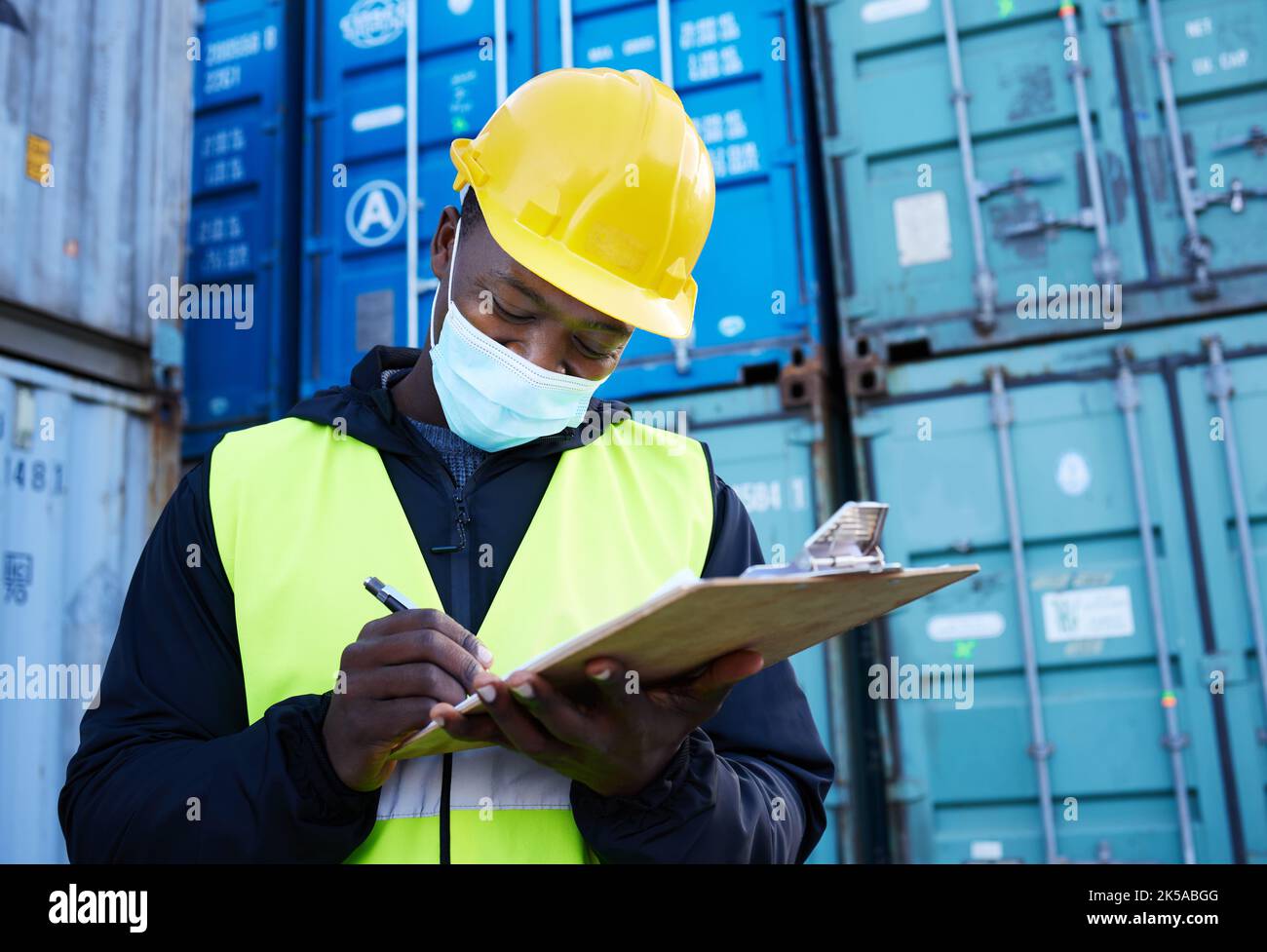 Logistikmitarbeiter, Containerhafen und Covid, schwarzer Mann schreibt auf Inventar-Checkliste. Frachtwerft, Export und Sicherheit für den Schifffahrtshafen Mitarbeiter oder Stockfoto