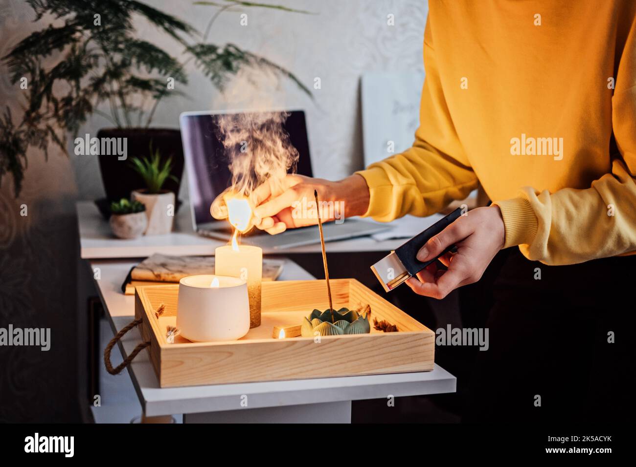Meditation, Entspannung nach der Arbeit. Frau macht sich bereit, meditiert und zündet indischen Räucherstäbchen und Kerzen an. Frau Hände mit Rauch indian Stockfoto