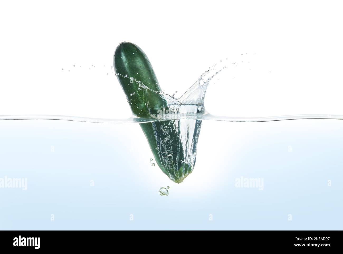 Zuchini spritzt in Wasser. Seitenansicht auf weißem Hintergrund. Stockfoto