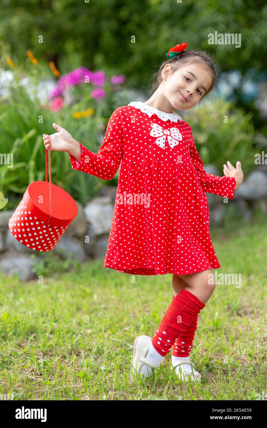 Schönes Mädchen in einem roten Kleid mit Polka im Sommergarten Stockfoto