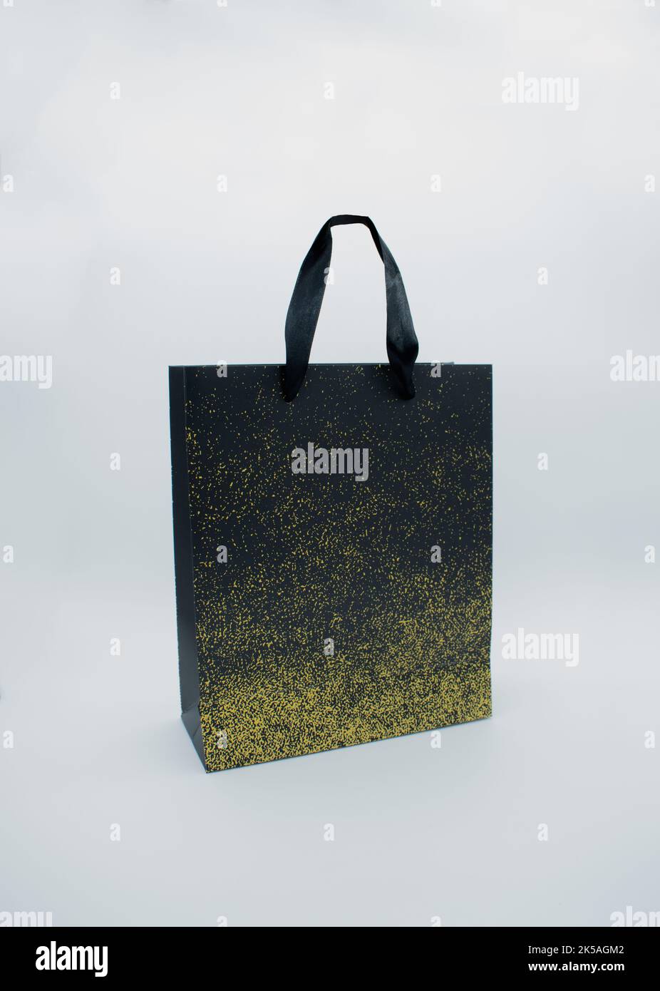 Schwarze Papiertasche mit goldenen Punkten auf weißem Hintergrund Stockfoto