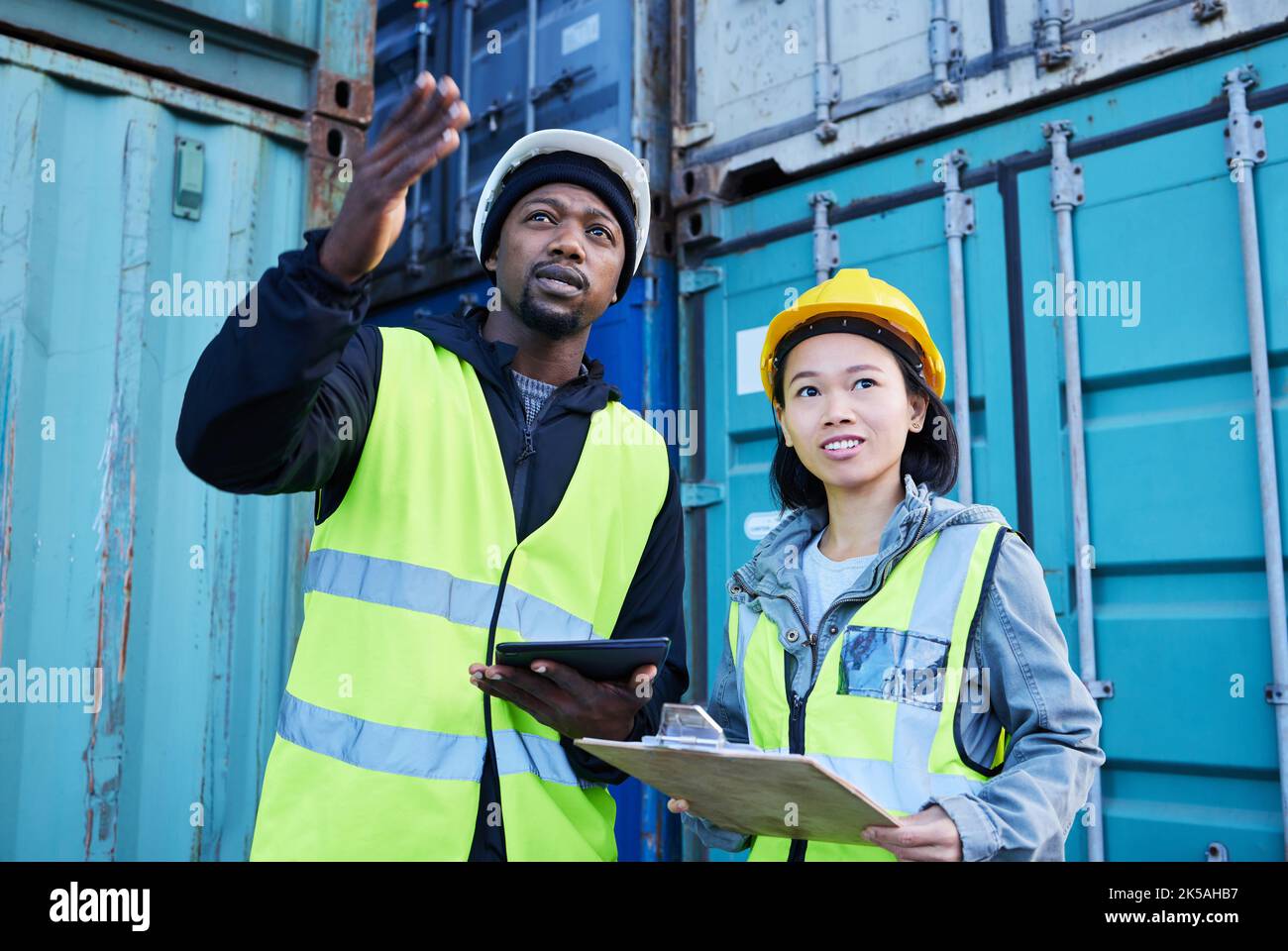 Logistik, Checkliste und Liefermanager in Kommunikation mit Industriearbeitern Lager-, Fracht- und Inventarkontrolle. Teamarbeit, Frau und afrikanischer Mann Stockfoto