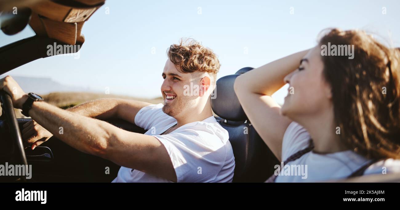 Roadtrip, glückliches Paar und Reisen, während in einem Cabrio-Auto für frische Luft, Abenteuer und Reise mit Partner genießen Reise, Liebe und Freiheit. Mann Stockfoto