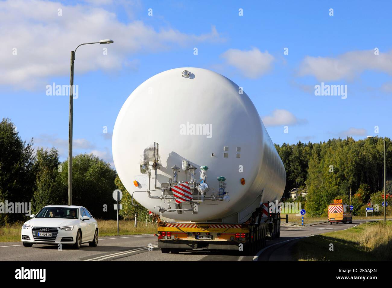 Rückansicht des Überlasttransports eines LNG-Lagersilos im Straßenverkehr, unterstützt durch ein Pilotfahrzeug. Salo, Finnland. 22. September 2022. Stockfoto