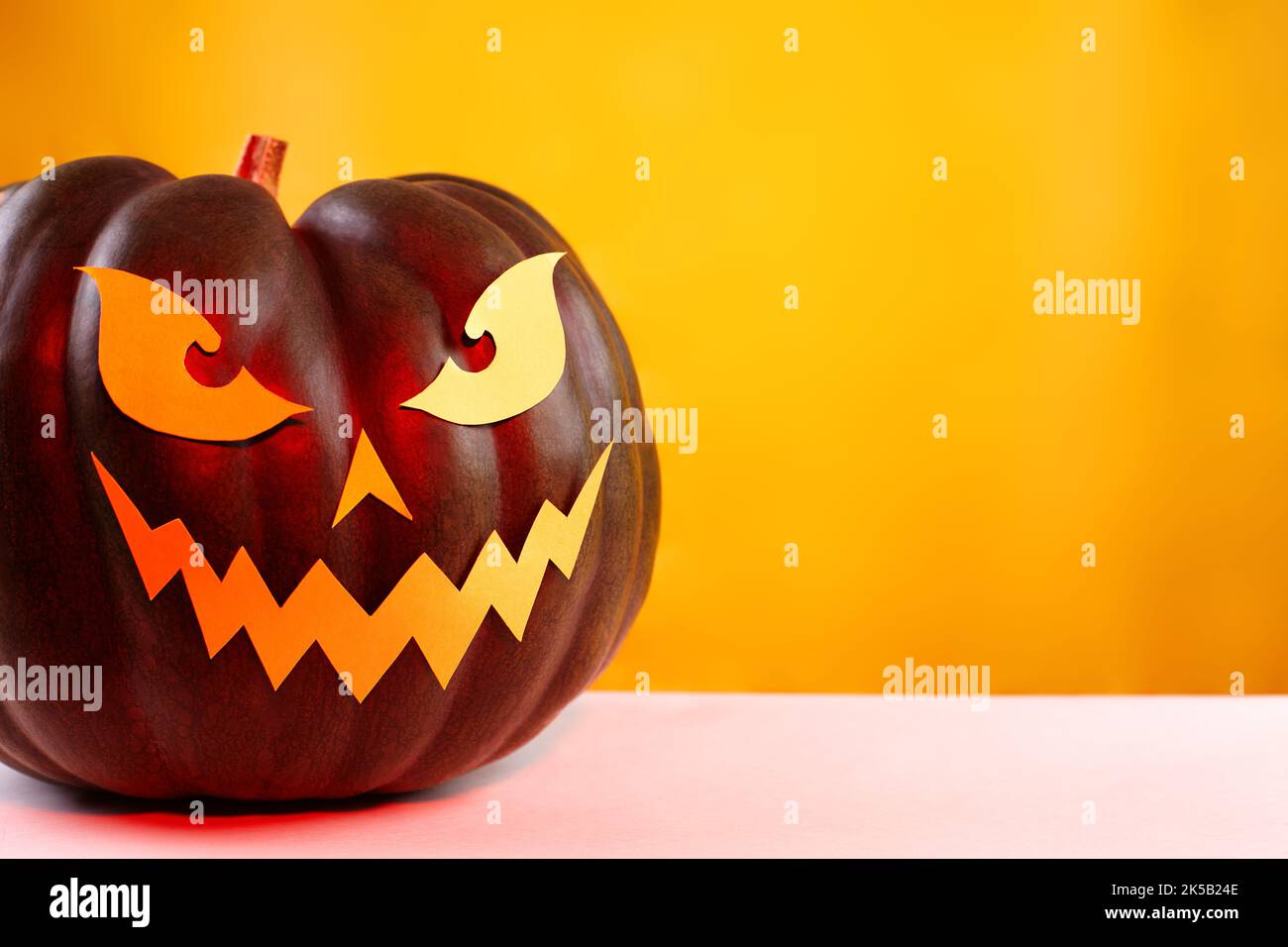 Halloween Kürbis mit Papier geschnitten Gruselgesicht auf einem gelben Hintergrund. Jack Halloween. Lächle Jack Pumpkin Stockfoto