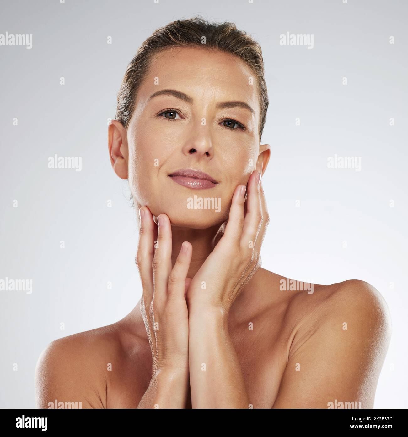 Gesicht, Schönheit und Hautpflege mit reifen Frauenhänden, die ihre Haut in einem Studio auf grauem Hintergrund berühren. Produkt, Anti-Aging und Kosmetik mit einem Weibchen Stockfoto