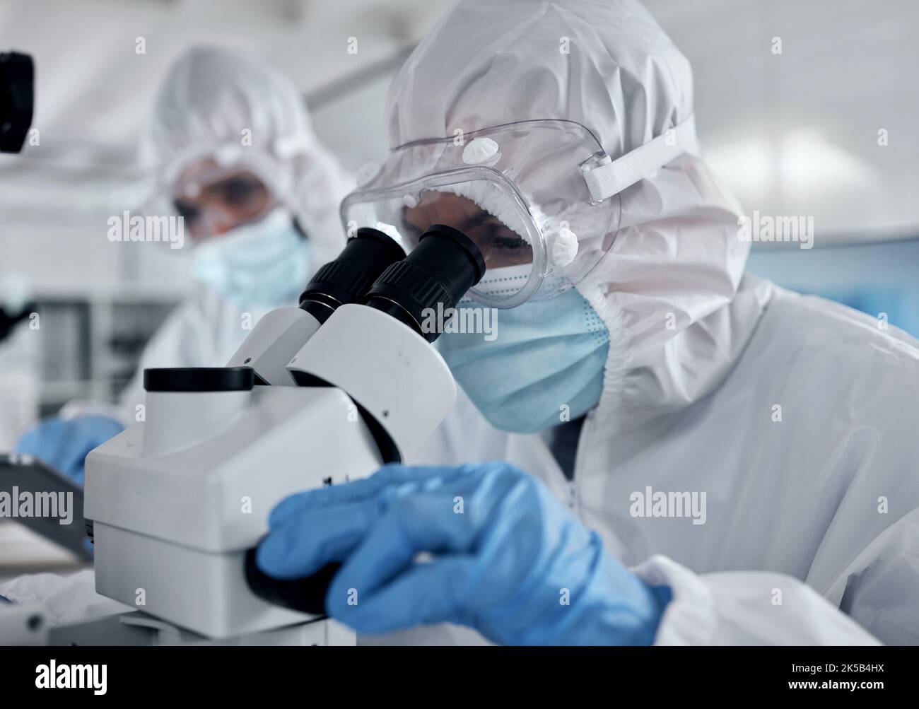 Hazmat Anzug Wissenschaftler, Mikroskop und Laborforschung Analyse, dna-Test und Impfstoffentwicklung von medizinischen Bakterien Risiko. Wissenschaftsteam Stockfoto