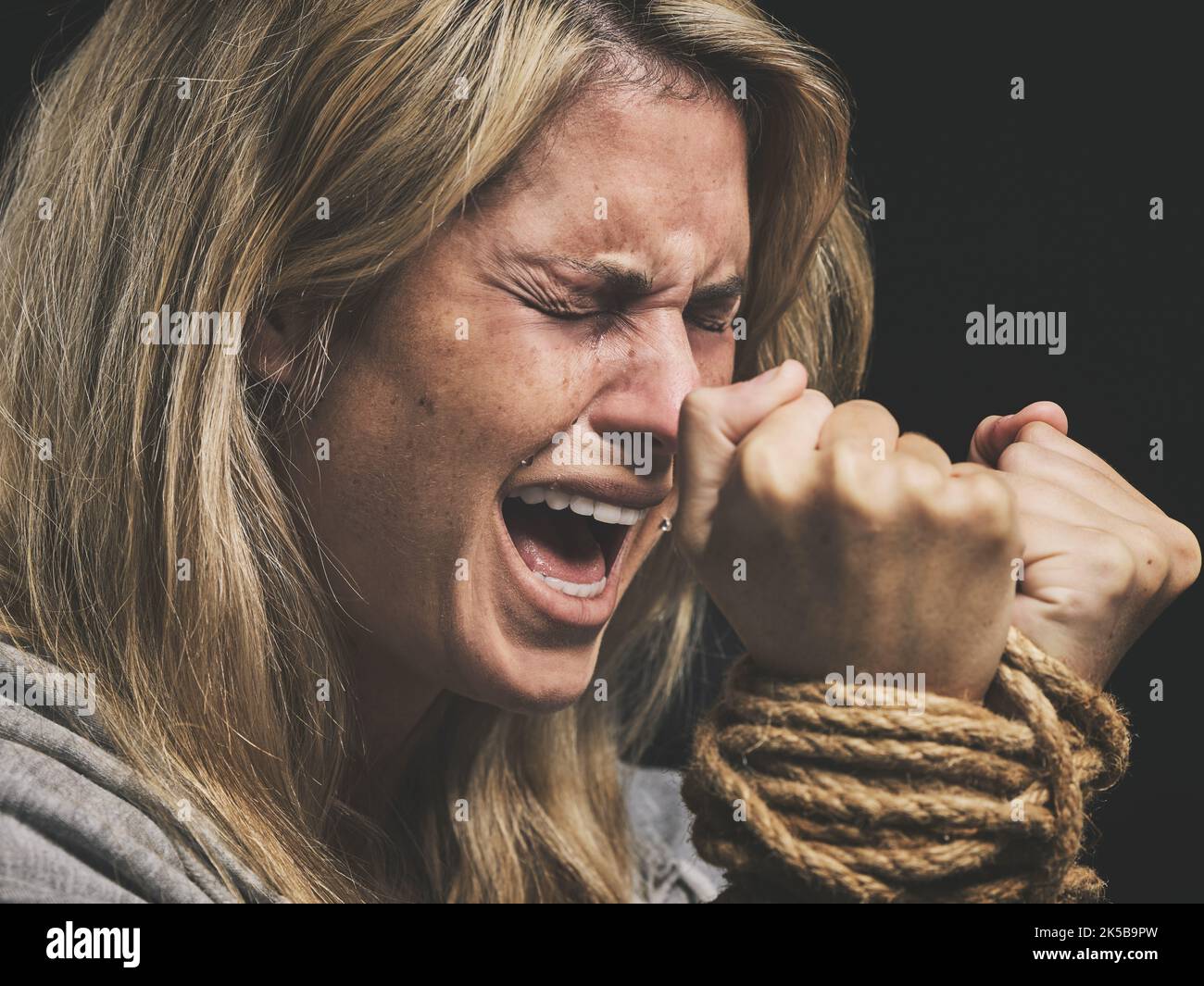 Gefahr, verängstigt und Horror Frau schreit um Hilfe mit Händen binden und durch Seil auf schwarzem Studio Hintergrund gefangen. Gewalt, traurig oder Angst weiblich mit Stockfoto