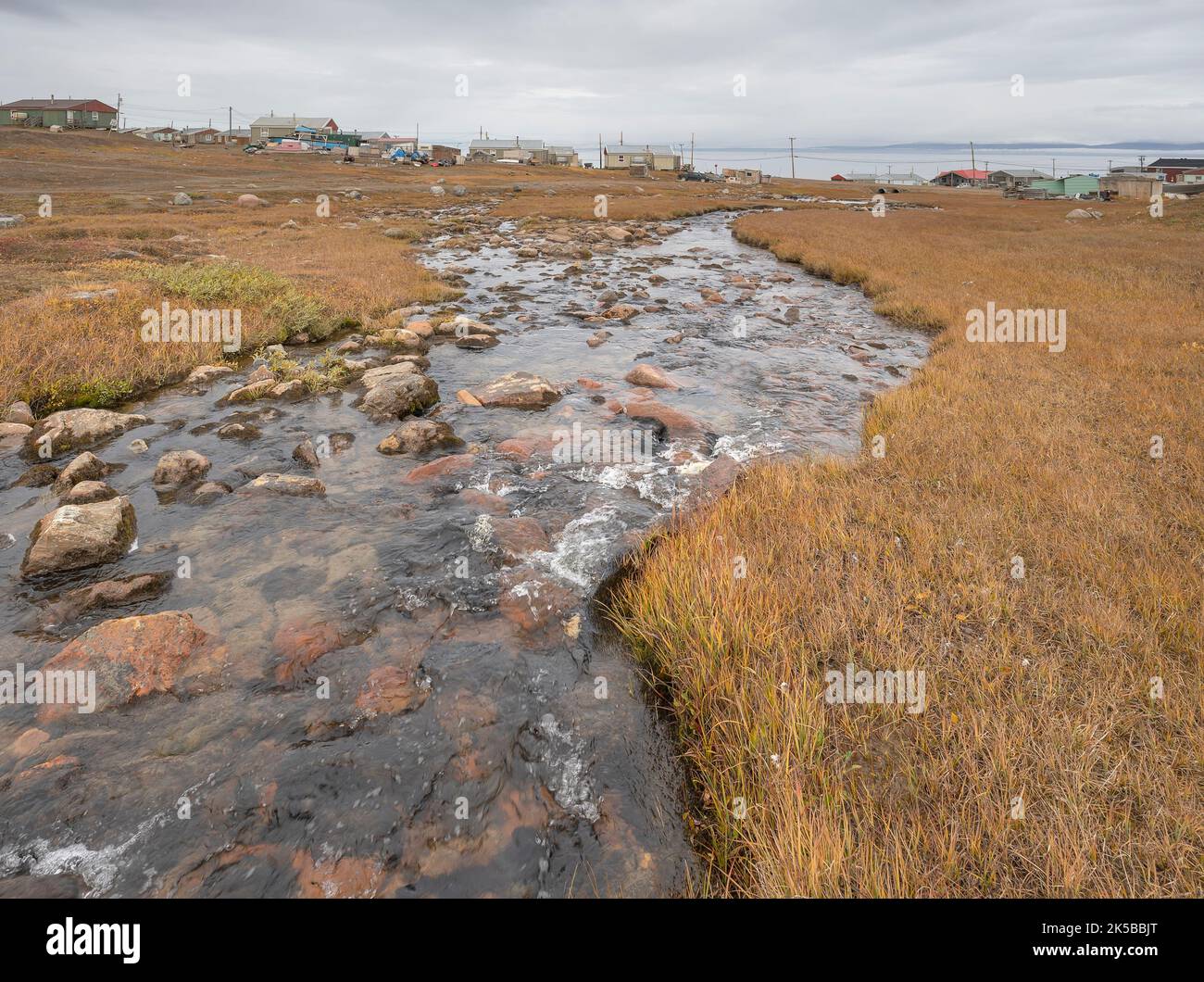 Bach, der durch das arktische Dorf Pond Inlet am Arktischen Ozean fließt Stockfoto