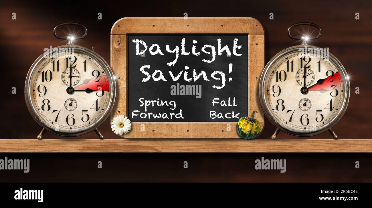 Sommerzeit, Frühling vorwärts und Herbst zurück (Herbst zurück). Zwei Wecker und eine Tafel mit Holzrahmen auf einem Holzregal. Stockfoto