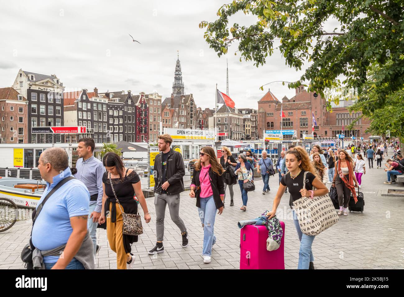 Einwohner und Touristen machen einen Spaziergang entlang der Grachtenrundfahrten auf dem Damrak im Zentrum von Amsterdam. Stockfoto