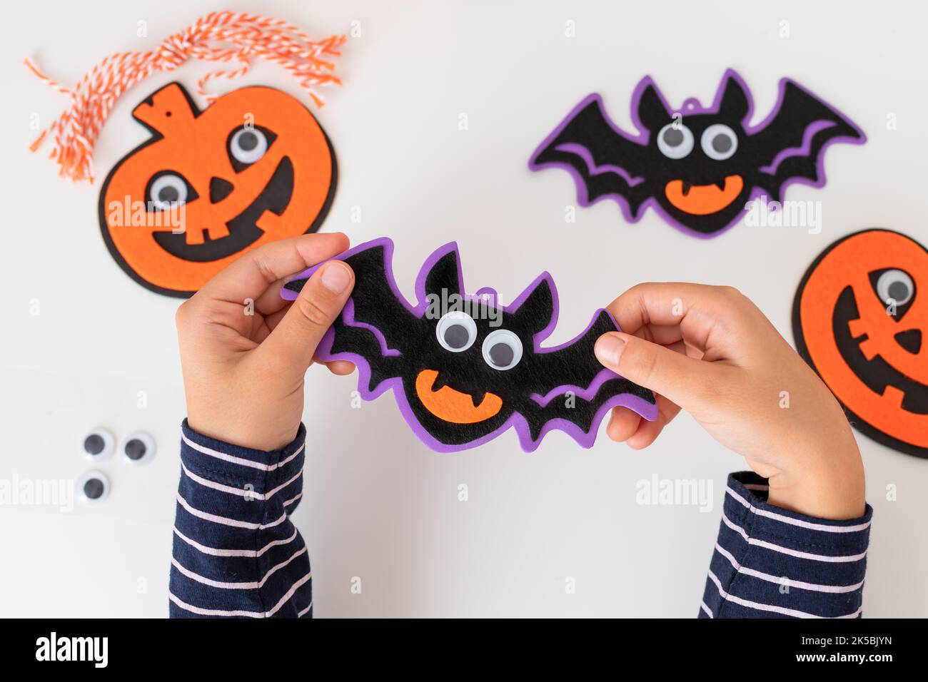 Kinderhände halten halloween Fledermaus Dekorationen mit gruseligen Gesicht Stockfoto