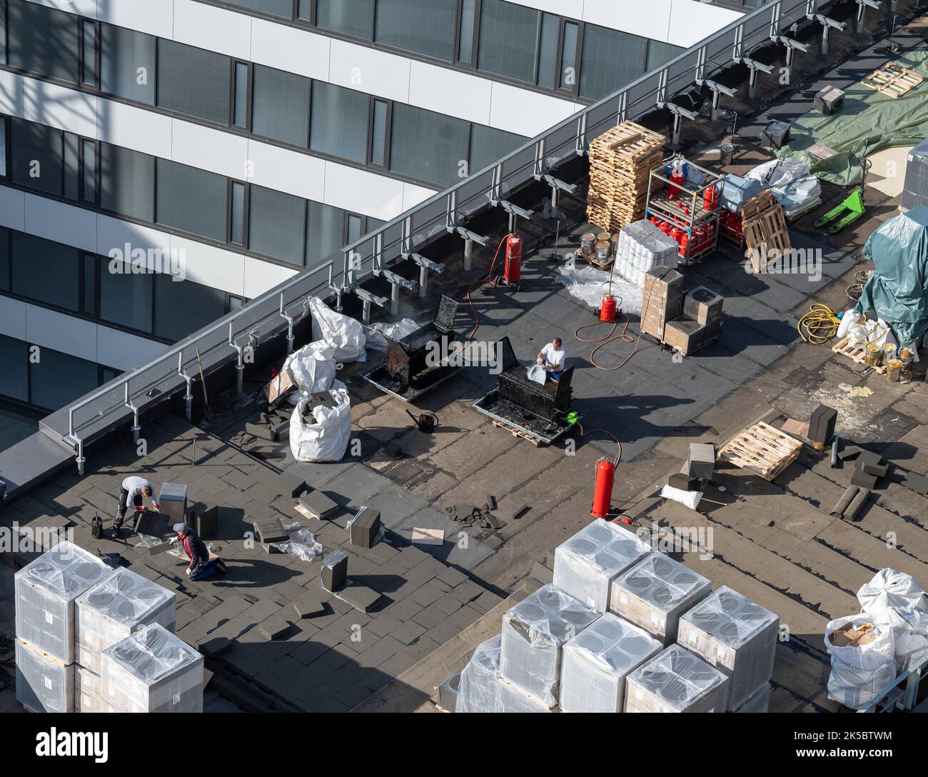 Vogelperspektive auf eine Dachbaustelle. Professionelle Bitumen-Abdichtung auf einem flachen Gebäude. Stockfoto